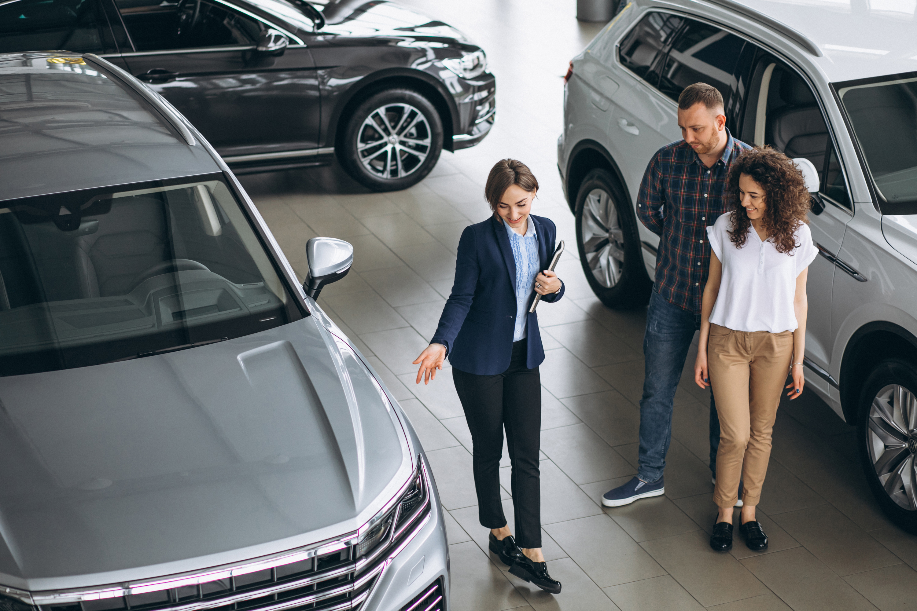 young-couple-talking-sales-person-car-showroom.jpg